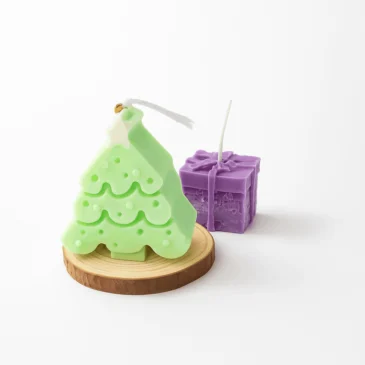 cdc0e792-2034-4e12-8c48-a6b51a021d98 kerst cadeau kaarsen – groene kerstboom en paarse cadeaukaars van sojawas op houten onderzetter