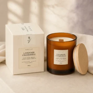 scentulp-geurkaars-lavendel-kamille-340-g.webp Sfeervol verpakte geurkaars in amberkleurig glas met houten deksel naast een witte doos.